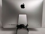 a silver apple computer with a black cord attached to it