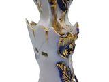 a white vase with a blue and gold decoration on it