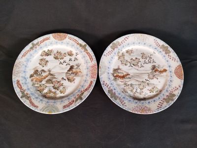 deux assiettes ornées d'oiseaux et de fleurs, posées sur une surface noire
