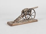 maquette ancienne en fonte représentant un canon, posée sur un socle en bois