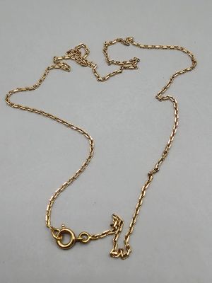 a close up of a gold necklace with a chain on a white surface