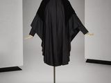 une image représentant un mannequin vêtu d'une robe noire dans une pièce blanche