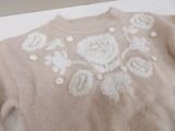 a pink sweater with white flowers on it sitting on a table