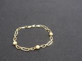a close up of a gold chain bracelet on a black surface