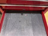 a red tool box with a red handle on the floor