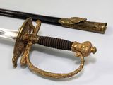 a sword with a gold handle on a white surface