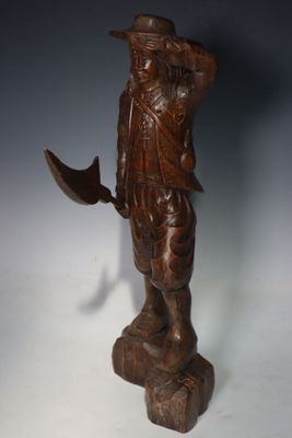 une image représentant une statue en bois d'un homme portant un chapeau et une épée