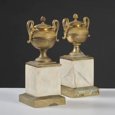 pair of antique brass urns on marble bases on a white surface