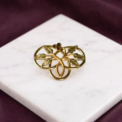une image représentant une bague en or ornée de feuilles, posée sur une surface en marbre