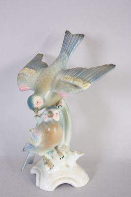 a figurine of a bird and two birds sitting on a branch