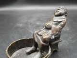 statue en bronze représentant une femme assise sur un bol, tenant un anneau à la main