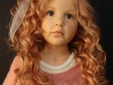 doll with red hair wearing a pink sweater and a white bow