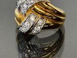 une image d'une bague en or et diamants posée sur une surface réfléchissante