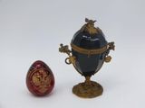 a red and black egg next to a gold and black egg