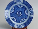 chinese blue and white plate with a dragon design on a stand