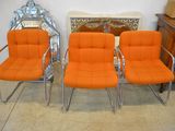 three orange chairs sitting next to each other in front of a mirror