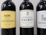 three bottles of red wine are lined up on a table