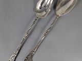 two silver spoons and a fork on a gray surface
