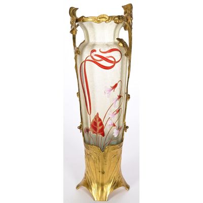 un vase en verre avec un socle doré et un motif floral