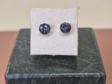a close up of a pair of blue sapphire earrings on a marble block