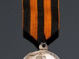 une vieille médaille entourée d'un ruban et une médaille surmontée d'une couronne