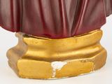 a statue of a man in a red robe on a gold pedestal