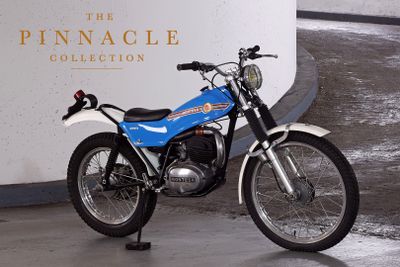 a blue and white motorcycle parked in front of the pinnacle collection sign