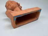 a clay sculpture of a baby head on a shelf