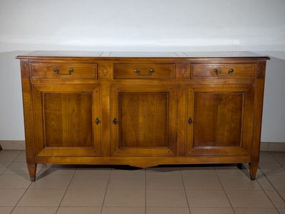a wooden sideboard with marble top on a tiled floor