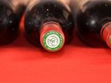 four bottles of wine are lined up on a red surface