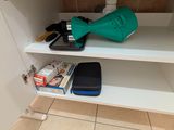 un sèche-cheveux vert posé sur une étagère dans une salle de bains