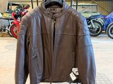 une veste en cuir suspendue à un porte-vêtements dans un garage, avec des motos en arrière-plan