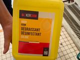 une personne tenant un flacon de produit dissuasif devant une pile de produits d'entretien