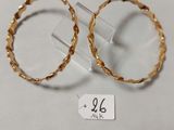 une paire de boucles d'oreilles en or posées sur une surface blanche