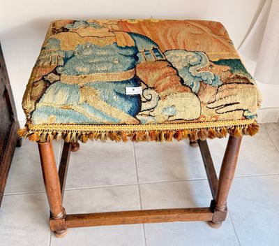un petit tabouret recouvert d'une tapisserie, dans une pièce