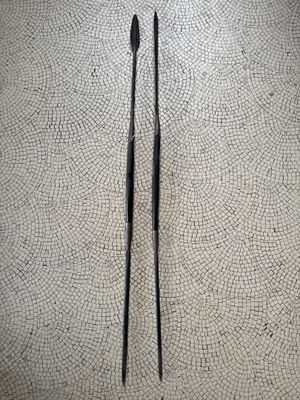 two pairs of black chopsticks sitting on a tile floor