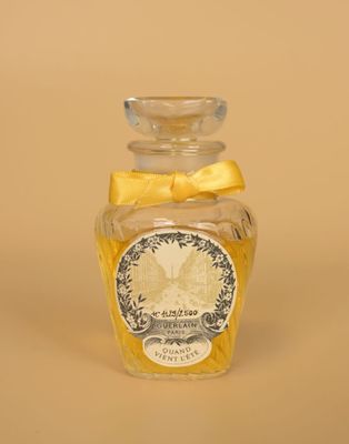 une petite bouteille en verre ornée d'un nœud jaune