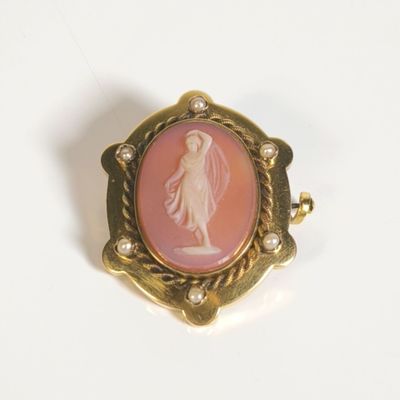 une image d'une broche rose et dorée représentant une femme
