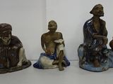 three figurines of people sitting on a white surface with a white background