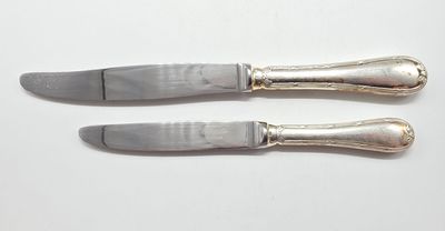 une paire de couteaux plaqués argent posés sur un fond blanc