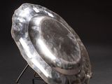 silver plate sitting on a stand on a black surface