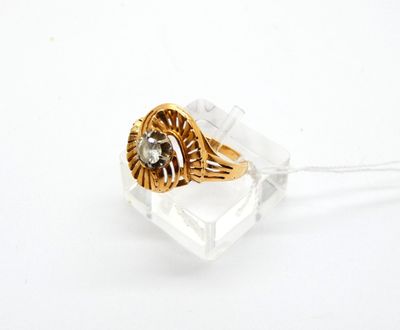 une photo d'une bague en or et diamants posée sur un morceau de verre transparent