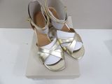 pair of white and gold sandals on display on a white surface
