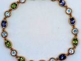 a close up of a gold bracelet with blue and green stones