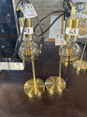 deux lampes dorées posées sur une table, avec des étiquettes de prix dessus
