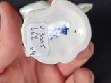 a hand holding a small figurine of a cat with a tag on it