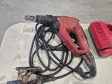 a red drill and a corded drill on a table