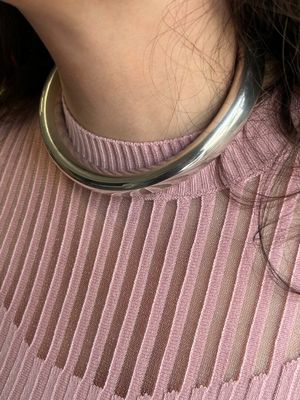La femme porte un pull rose et un collier en argent.