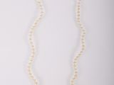 un collier de perles blanches avec un fermoir en argent sur fond blanc