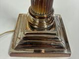 a silver lamp that is sitting on a white table